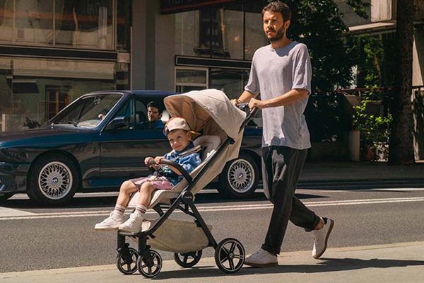 Ekskluzywny wózek spacerowy Nuna TRVL LX BMW podczas miejskiego spaceru z dzieckiem.