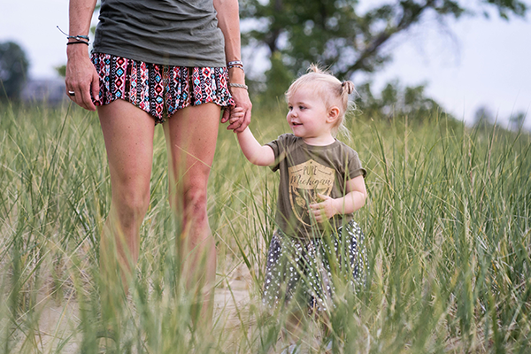 Mała dziewczynka trzymająca za rękę mamę podczas spaceru, symbol pierwszych decyzji rodziców i wyboru imienia dla dziecka