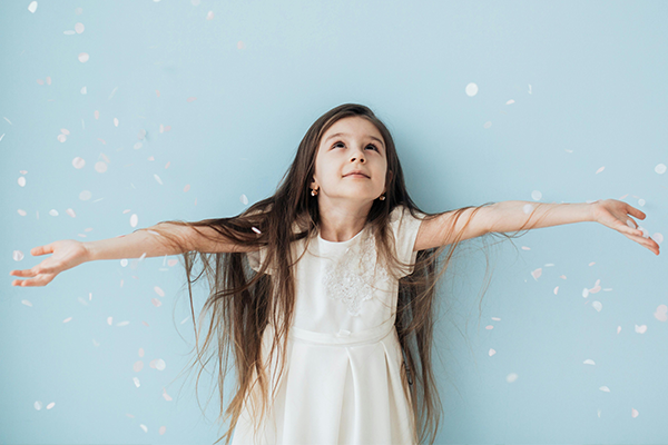 Dziewczynka z rozłożonymi ramionami, symbol marzeń, wolności i kształtowania tożsamości dziecka przy wyborze imienia