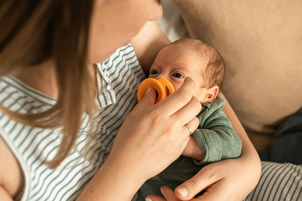 Rodzic uspokajający niemowlę smoczkiem, pomoc w regulacji emocji w czasie skoku rozwojowego