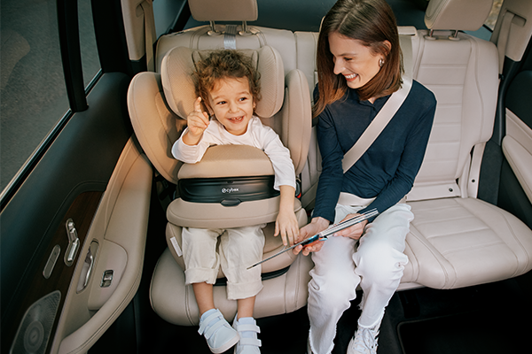 Dziecko siedzące w foteliku Cybex Pallas G3 z mamą na tylnej kanapie samochodu